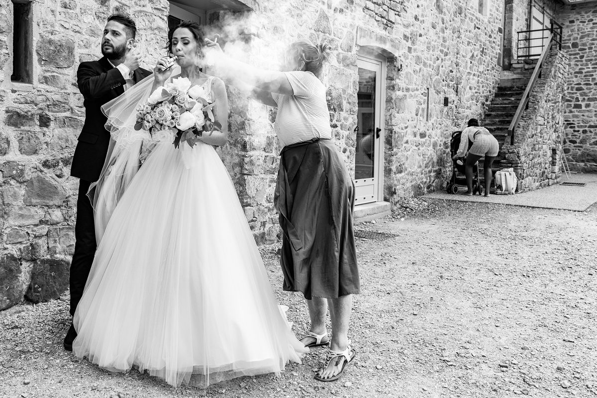 Photographe mariage Manche — mariée pause cigarette mur pierre normand — Arnaud Chapelle